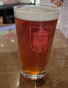 A glass of beer on a wooden table at Balsam Lake Brewery.