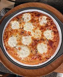 A pizza is sitting on a wooden plate at Balsam Lake Brewery.