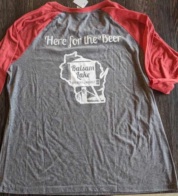 A gray and red baseball tee with the slogan "here for the beer" and "balsam lake brewery market" printed on it.