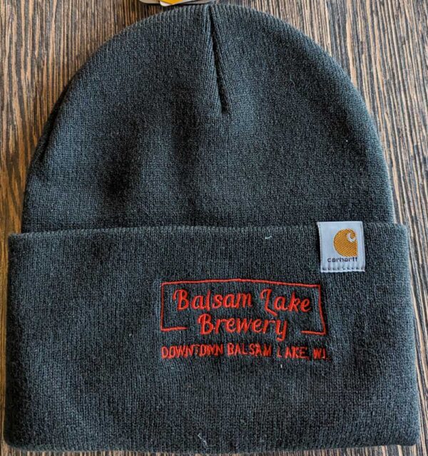 A black Carhartt winter cap with a "balsam lake brewery downtown balsam lake, wi" logo patch.