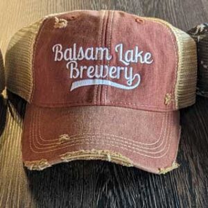 Three Distressed Baseball Caps with "Balsam Lake Brewery" embroidered on the front, displayed on a wooden surface.
