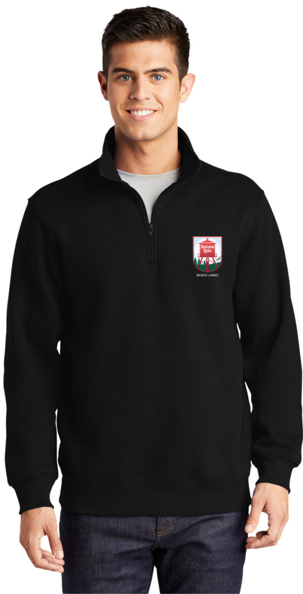 A man wearing a Quarter Zip Sweatshirt Black with a red crest.