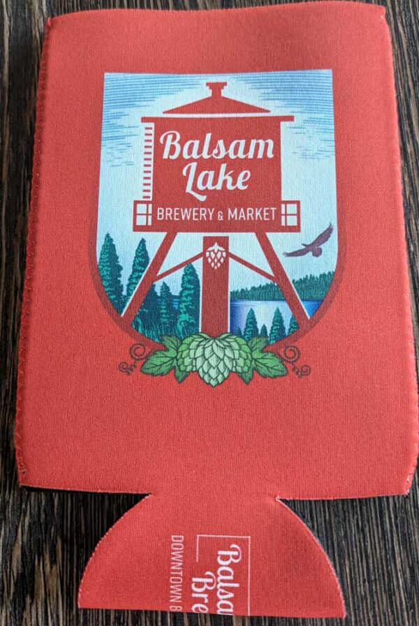 A red Crouler Koozie with "balsam lake brewery & market" logo printed on it.