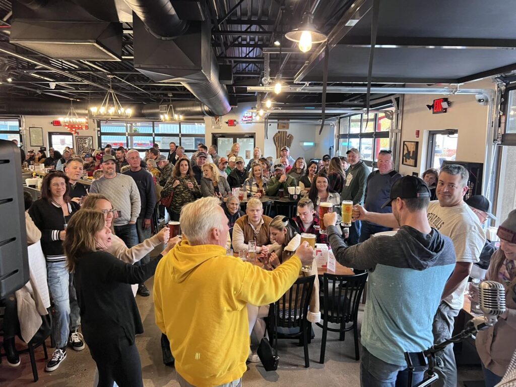 A crowd of people standing in a restaurant at Balsam Lake Brewery.