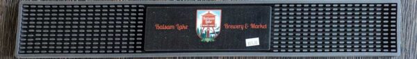 A black Rail Mat with an inset displaying a red drink cup and the text "welcome to" above and "Balsam Lake Brewery" below it.