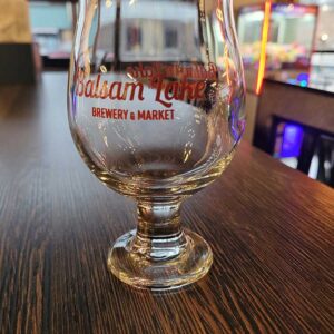 A 10 OZ Tulip Glass of beer sits on a table at Balsam Lake Brewery.
