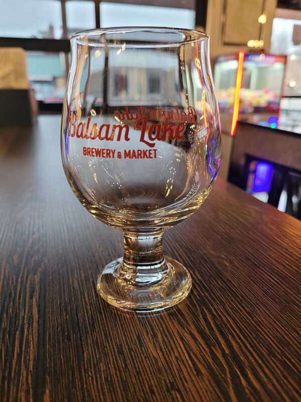 A 10 OZ Tulip Glass of beer sits on a table at Balsam Lake Brewery.