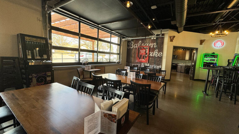 Interior of a casual dining area with wooden tables, menu holders, and a large promotional banner.