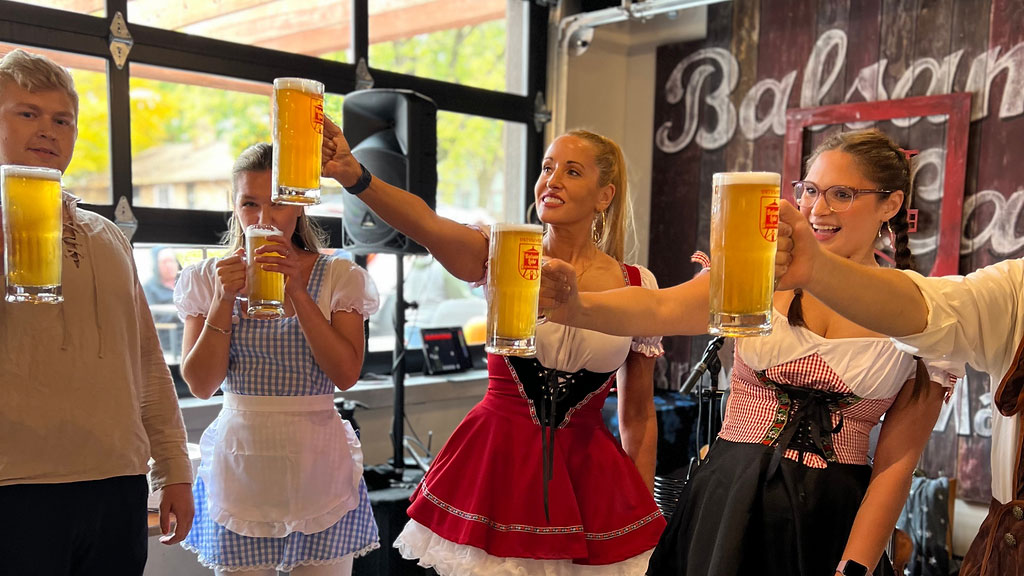 People in traditional german attire holding up large beer steins.